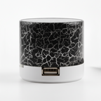 Small cylindrical device with cracked glass design next to a smartphone on a white background