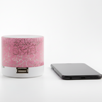 Pink and white cylindrical power bank with a cracked glass design next to a smartphone on a white background